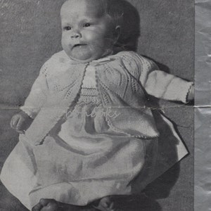 May include: Black and white image of a baby wearing a knitted matinee coat and dress. The image includes text that reads "MATINEE COAT UP TO 9 MTHS" and "Use P & B wools to be sure."