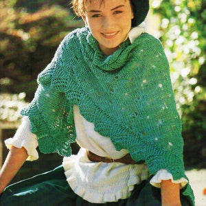 Puede incluir: Una mujer con un chal de punto verde, una camisa blanca y una falda verde oscuro. Lleva una boina azul oscuro.