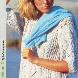 May include: A white knitted sweater with a cable knit pattern and a delicate lace design. The sweater has a round neckline and three-quarter sleeves.