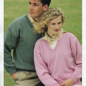 May include: A couple wearing matching knit jumpers. The man is wearing a teal jumper and the woman is wearing a pink jumper. Both jumpers have a v-neck and are 4 ply.