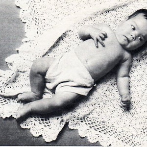 May include: A baby wearing a white diaper and lying on a white crocheted blanket.
