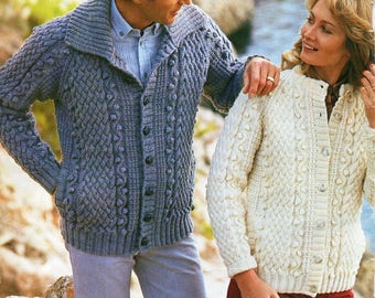 Pode incluir: Um casal usando cardigans de malha. O homem usa um cardigan cinza com um padrão texturizado e gola xale. A mulher usa um cardigan creme com um padrão semelhante. Ambos os cardigans têm fechos de botão. O texto "2/3" é visível.