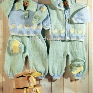May include: Two baby outfits, each with a sweater, trousers, and mittens or socks, are displayed. The outfits are light blue with yellow duck accents. Wooden boxes with yellow ribbons are in the foreground. The background is wooden.