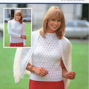 May include: A white knitted sweater and cardigan set with a lacy pattern. The sweater has a round neckline and long sleeves. The cardigan has a shawl collar and long sleeves. The set is shown on a model wearing a red skirt.