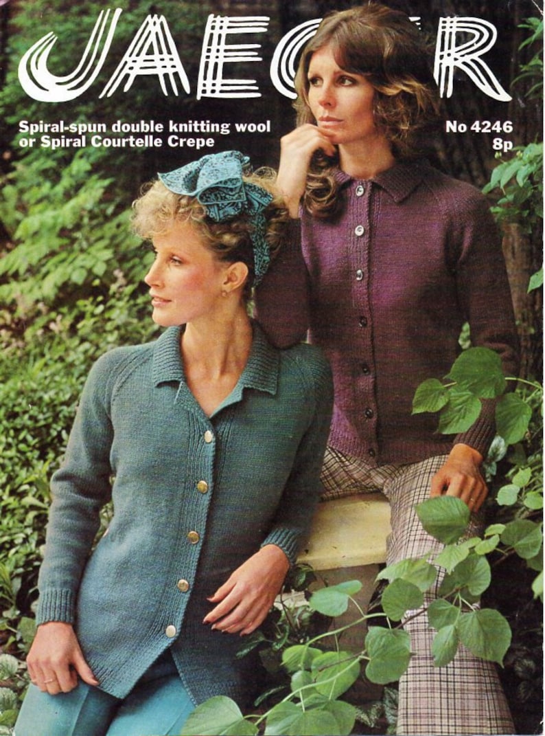 May include: Two women wearing knitted cardigans. The woman on the left is wearing a teal cardigan with a button closure and the woman on the right is wearing a purple cardigan with a button closure. Both women are standing in front of a leafy green background.