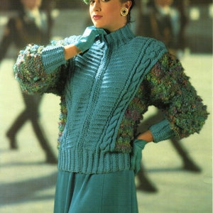 May include: A teal blue knitted jumper with a cable knit pattern and a fluffy green and blue trim. The jumper is worn with a matching teal blue skirt.