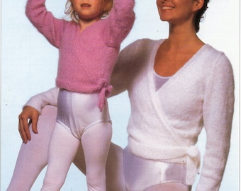 May include: A woman and a young girl wearing matching white and pink knit sweaters. The woman is wearing a white sweater with a wrap style and the girl is wearing a pink sweater with a wrap style. Both are wearing white tights.