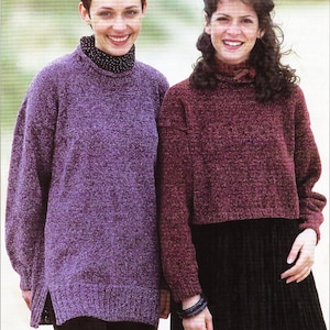 May include: Two women wearing jumpers. The woman on the left is wearing a purple jumper with a black and white polka dot turtleneck. The woman on the right is wearing a burgundy jumper with a black skirt.