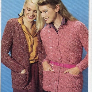 May include: Two women wearing knitted cardigans. The woman on the left is wearing a burgundy cardigan with a yellow blouse underneath. The woman on the right is wearing a pink cardigan with a white blouse underneath. Both cardigans have pockets and button closures.