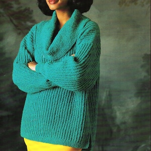 Könnte beinhalten: Ein tealblauer Strickpullover mit einem breiten, umgeklappten Kragen und einem gelben Rock. Der Pullover hat eine gerippte Struktur.