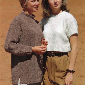 May include: Two women wearing jumpers. The woman on the left is wearing a brown jumper and white trousers. The woman on the right is wearing a white jumper and brown trousers with a brown belt.