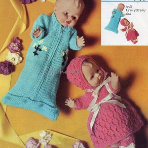 Könnte beinhalten: Strickmuster für ein Baby-Puppenoutfit. Das Muster enthält Anleitungen für einen türkisfarbenen Schlafsack mit weißen Blumen und ein rosa Kleid mit einer weißen Schärpe. Das Muster ist für eine 30 cm große Puppe.