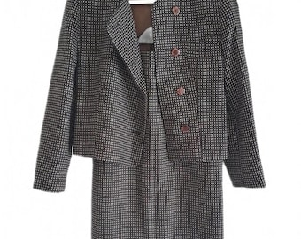 May include: A two-piece women's suit with a jacket and skirt. The jacket is a cropped style with three brown buttons and a round neckline. The skirt is knee-length. Both pieces feature a black and white checkered pattern.