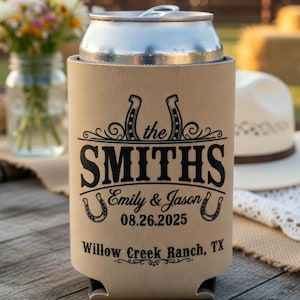 May include: A tan can cooler with black text that reads "the Smiths" above "Emily & Jason" and the wedding date "08.26.2025". The bottom of the cooler says "Willow Creek Ranch, TX". A silver can sits inside the cooler.