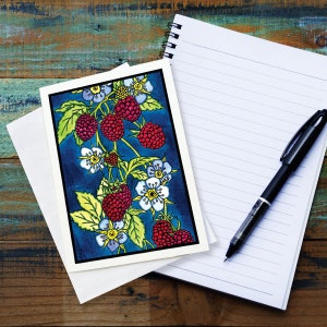 May include: A greeting card with a colorful illustration of a raspberry plant with red berries and white flowers on a dark blue background.