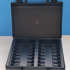 May include: An open, black plastic carrying case with a handle on top and a latch. The interior is divided into compartments, likely for organizing small items. The case is designed for easy transport and storage.