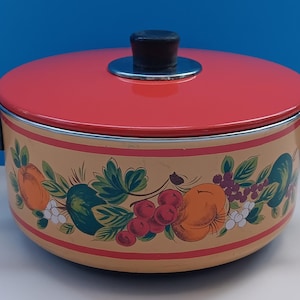 Pode incluir: Uma panela de esmalte vermelho com uma alça e uma tampa pretas. A panela tem um design floral com frutas e folhas em tons de verde, laranja, amarelo e branco.