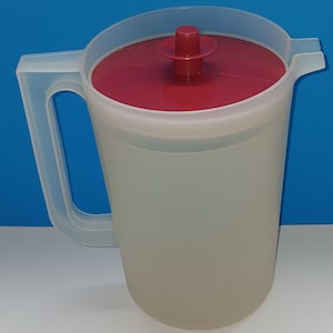 Puede incluir: Una jarra de plástico translúcido con tapa y asa rojas. La jarra tiene una capacidad aproximada de 2 litros. La tapa tiene un botón central para facilitar la extracción. La jarra está diseñada para servir bebidas.