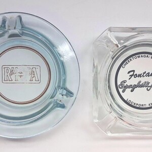May include: Two clear glass ashtrays. The circular one features the text RAMADA in a rectangular border. The square one features the text Fontana's Spaghetti House, CHEEKTOWAGA: 822-7918, and LOCKPORT: 433-4446 printed in a circular black border.