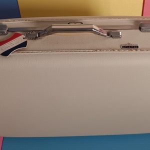 May include: A vintage white hard-sided suitcase with a silver handle and a luggage tag that says "Continental Airlines".