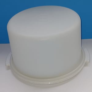 以下が含まれることがあります： 透明なプラスチック製のベースが付いた白いプラスチック製のケーキドーム。ドームは滑らかで、わずかにカーブしています。ベースはわずかにテクスチャ加工されています。