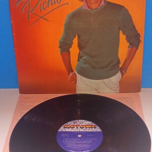 May include: Album cover featuring Lionel Richie in a green sweater and white pants against an orange background. The album title, "Lionel Richie," is in cursive. A vinyl record with a Motown label is in the foreground.