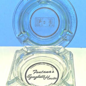 May include: Two clear glass ashtrays. The top round ashtray features a rectangular logo with the letters RA. The bottom square ashtray displays a circular label reading Fontana's Spaghetti House, Cheektowaga: 822-7918, and Lockport: 433-4446.