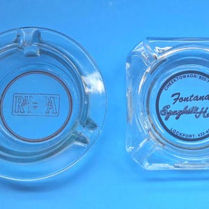 May include: Two clear glass ashtrays. The circular ashtray features a rectangular logo with the text RA-PA in the center. The square ashtray features a circular logo with the text Fontana's Spaghetti House, Cheektowaga: 822-7918, and Lockport: 433-4446.