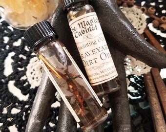 May include: Two small glass bottles with brown liquid and labels that read "The Magic Cabinet Anointing Oils  Grave Yard Dirt Oil".
