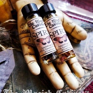 Spirit Guide oil in a 2 dram bottle. There's a lovely red butterfly on the label with the words The Magick Cabinet and Anointing oil. They stand on three tarot cards face down.