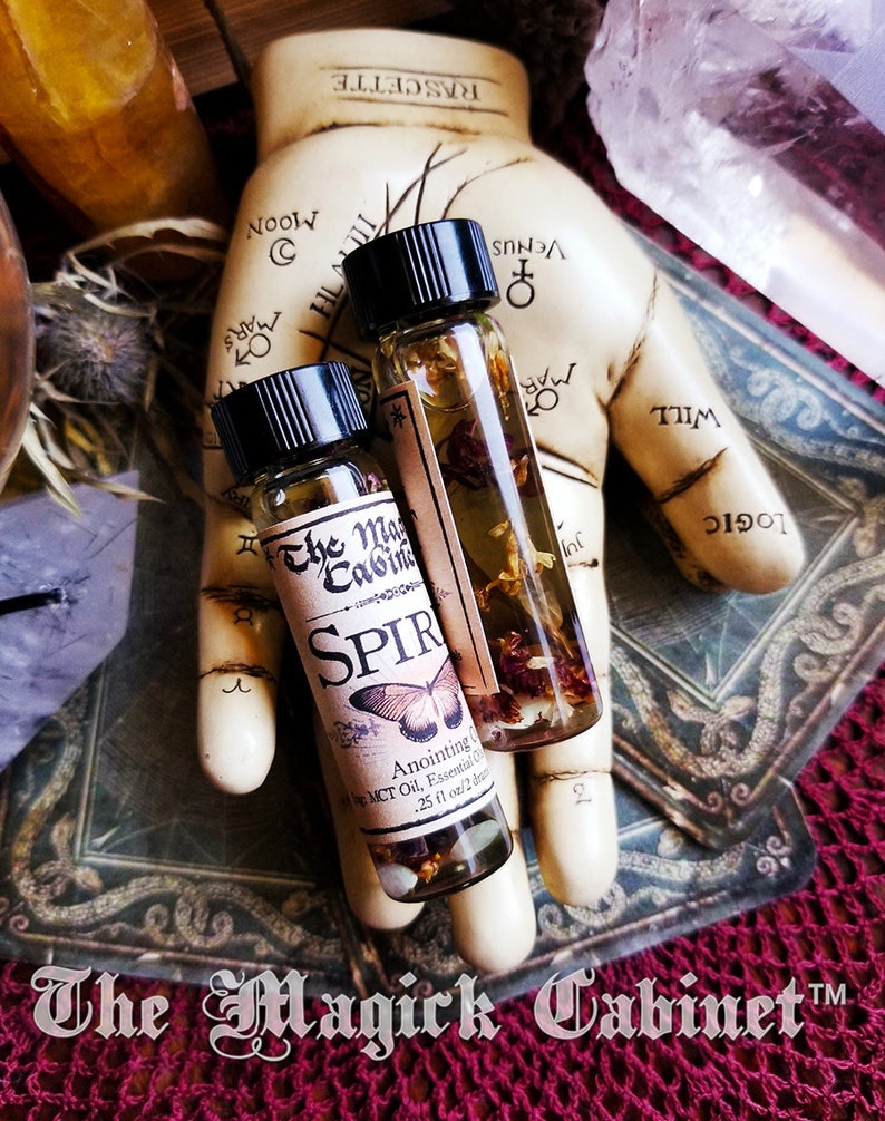 Spirit Guide oil in a 2 dram bottle. There's a lovely red butterfly on the label with the words The Magick Cabinet and Anointing oil. They stand on three tarot cards face down.