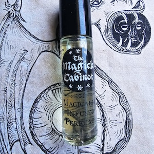 May include: A clear glass bottle with a black cap and a label that reads "The Magick Cabinet" and "Magically Infused Perfume".