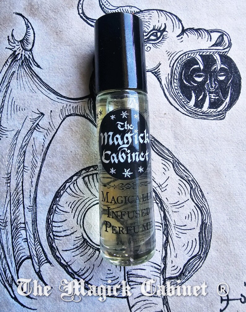 May include: A clear glass bottle with a black cap and a label that reads "The Magick Cabinet" and "Magically Infused Perfume".