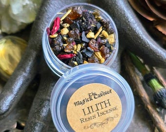 May include: A small, clear plastic container filled with a mix of dried herbs and resins. The lid features a brown label with the text "LILITH Resin Incense" and the brand name "The Magick Cabinet". The incense is displayed on a decorative, dark metal surface.