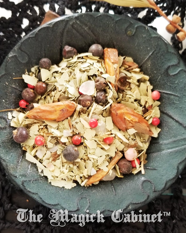 May include: A black bowl filled with a mixture of dried herbs, spices, and berries. The mixture includes dried leaves, pink Himalayan salt, red peppercorns, and juniper berries. The bowl is labeled "The Magick Cabinet TM".