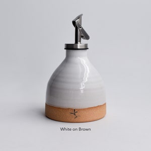 May include: White ceramic oil and vinegar bottle with a brown base and a stainless steel pour spout. The bottle is labeled "White on Brown".
