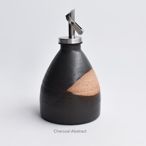 May include: A black and brown ceramic oil and vinegar bottle with a stainless steel pour spout. The bottle has a charcoal abstract design.