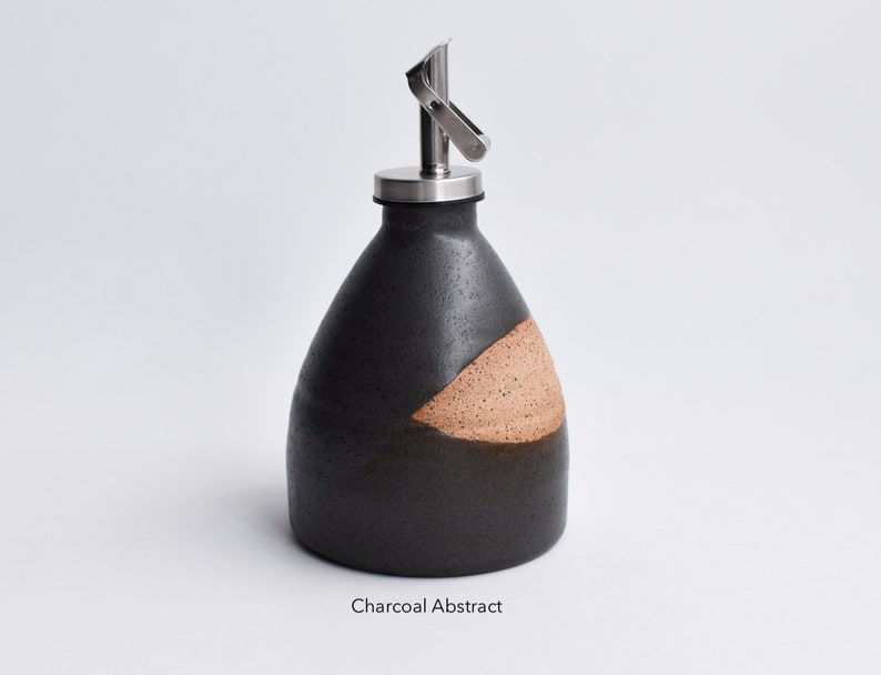 May include: A black and brown ceramic oil and vinegar bottle with a stainless steel pour spout. The bottle has a charcoal abstract design.