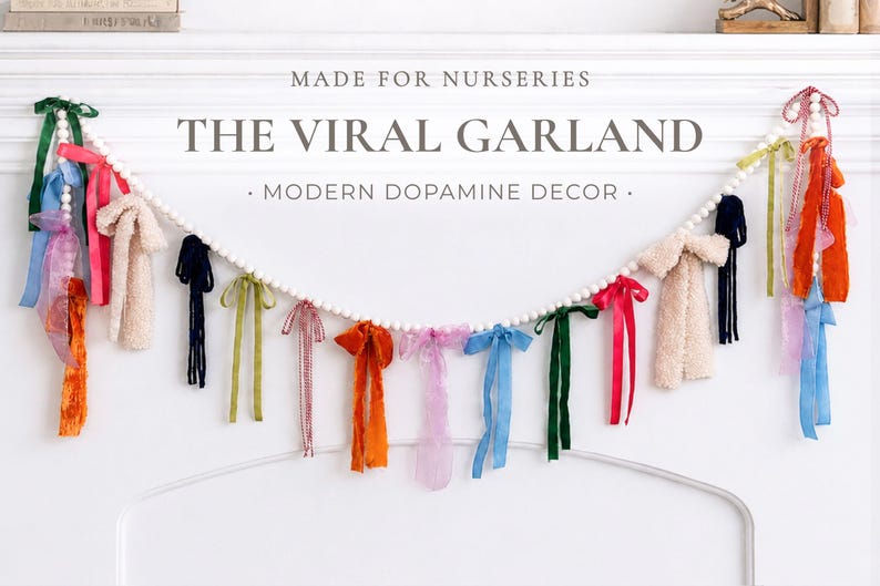 May include: A garland featuring white beads and a variety of colourful ribbons and fabric tassels. The ribbons are in shades of pink, orange, blue, green, and cream. The image text reads "MADE FOR NURSERIES" and "THE VIRAL GARLAND - MODERN DOPAMINE DECOR."