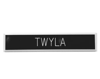 May include: A black name tag with silver trim and the name "TWYLA" printed in white.