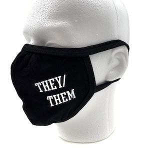 Peut inclure: Masque facial noir avec du texte blanc qui dit "THEY/THEM".