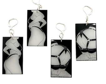 May include: Four pairs of black and white graphic earrings. Each earring features a rectangular pendant with a silver hook. The pendants display illustrations of figures in various poses, with a focus on the body.