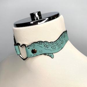 May include: A light blue leather choker with a heart-shaped clasp and an octopus design.