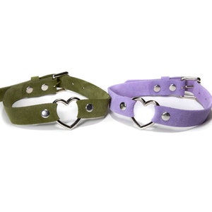 May include: Two suede choker necklaces with silver heart charms. One choker is green and the other is purple.