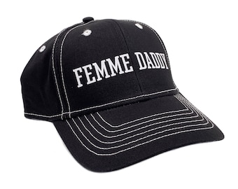 May include: Black baseball cap with white stitching and the text "FEMME DADDY" in bold white letters. The cap has a curved brim and a button on top. A stylish accessory for everyday wear.