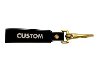 May include: Black leather keychain with a brass hook and the word "CUSTOM" embossed in silver lettering.