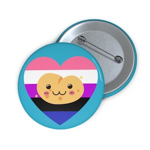 May include: A round, light blue button with a heart-shaped design featuring the non-binary pride flag and a cute, smiling potato character. The button has a metal pin back.