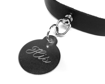 May include: Black leather choker necklace with a silver-tone pendant. The pendant is a rounded tag shape with the word "His" elegantly engraved in cursive script. The necklace has a simple, classic design.