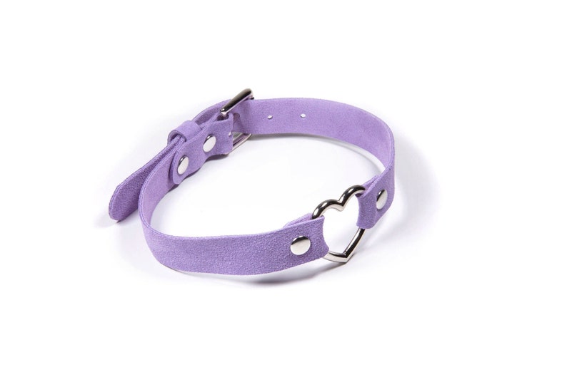 Lavender suede choker with a silver heart shaped ring in the middle. With a buckle closure and silver rivets holding it together.