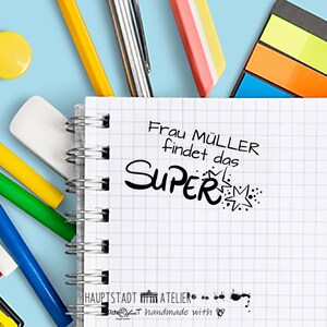 May include: A white notebook with a black spiral binding. The notebook has a black and white graphic of a star with the text "Frau M&uuml;ller findet das SUPER" on the front.